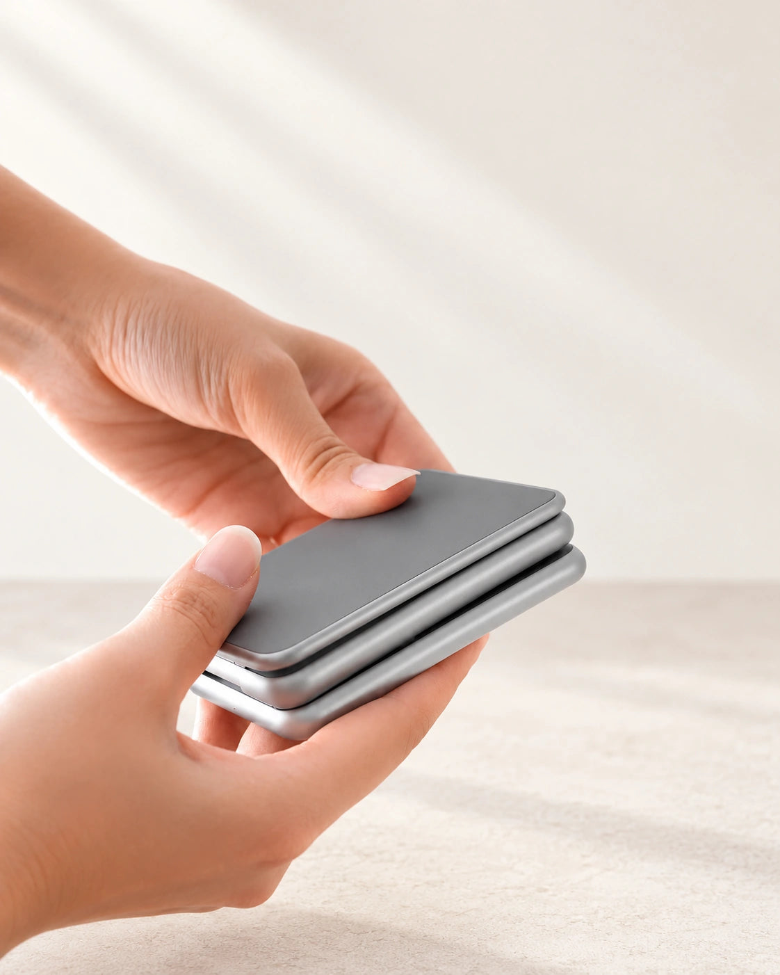 Hands folding the three original hinged panels of a gray charging stand for travel.