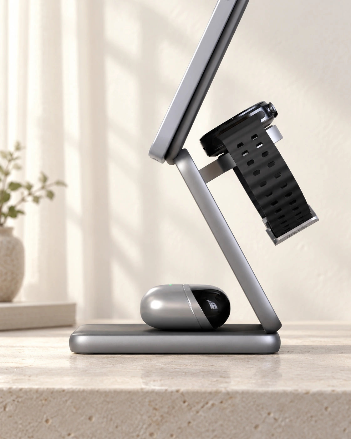Silver wireless earbuds resting on the base charging pad beneath the folding phone stand.